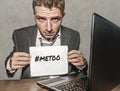 Frustrated businessman desperate at office computer desk holding notepad with the hashtag me too metoo as exploited employee Royalty Free Stock Photo