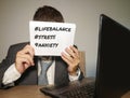 Frustrated businessman desperate at office computer desk holding notepad with the hashtag me too metoo as exploited employee Royalty Free Stock Photo