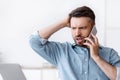 Frustrated businessman having problems with computer, talking on cellphone with customer support Royalty Free Stock Photo