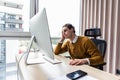 Frustrated businessman sitting on desk with hand on head in modern office Royalty Free Stock Photo