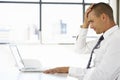 Frustrated Businessman Sitting At Desk In Office Using Laptop Royalty Free Stock Photo