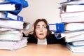 Frustrated businesswoman with stack of folders