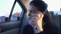 Frustrated businesswoman swearing on cellphone in car, overburdened with work