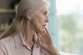 Frustrated concerned elderly woman looking away, touching chin