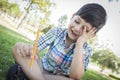 Frustrated Cute Young Boy Holding Pencil Sitting on the Grass Royalty Free Stock Photo