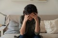 Frustrated depressed millennial woman sit on couch alone hug head