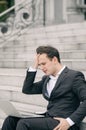 Frustrated and depressed young business man sitting on stairs while working with his laptop Royalty Free Stock Photo