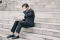 Frustrated and depressed young business man sitting on stairs while working with his laptop Royalty Free Stock Photo