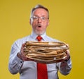 Frustrated executive worker over yellow background overworked holding piles of documents paper work. Royalty Free Stock Photo