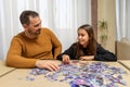 Frustrated father and his funny daughter doing puzzle in their living room Royalty Free Stock Photo