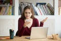 Frustrated female entrepreneur looking at cellphone and shruggin