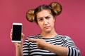 Frustrated hipster girl pointing finger at blank screen mobile phone isolated