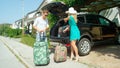 Frustrated husband keeps loading up the trunk of the couple`s SUV after wife brings even more suitcases before setting off on rela Royalty Free Stock Photo