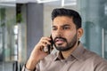 Frustrated Indian man talking on mobile phone in office Royalty Free Stock Photo