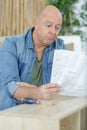 frustrated man reading instruction and putting together self assembly furniture Royalty Free Stock Photo