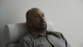 Frustrated man in shirt during therapy session in psychologist office. Silent bald middle age man portrait in armchair Royalty Free Stock Photo