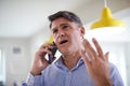 Frustrated Mature Man Receiving Sales Call At Home