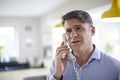 Frustrated Mature Man Receiving Sales Call At Home