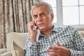 Frustrated Mature Man Receiving Unwanted Telephone Call At Home