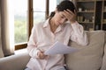 Frustrated millennial Hispanic woman feeling stressed reading letter.