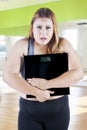 Frustrated overweight woman holding digital scales