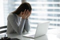 Frustrated overworked businesswoman covering face with hands, sitting at desk Royalty Free Stock Photo