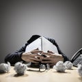 Frustrated and overworked man burying his head under a laptop computer