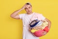 Frustrated overworked man posing with basin full of dirty clothes, having much home duties, stands with laundry basket, male Royalty Free Stock Photo