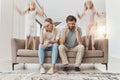Frustrated parents, sofa and headache with children jumping in living room chaos, ADHD or crazy home. Mother and father Royalty Free Stock Photo
