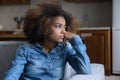 Frustrated pensive teenage African girl sitting on couch at home Royalty Free Stock Photo
