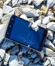 Frustrated phone on the . Glass shattered on rocks on a sma