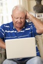 Frustrated Retired Senior Man Sitting On Sofa At Home Using Laptop Royalty Free Stock Photo