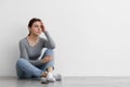 Frustrated sad worried caucasian young woman waiting for call and thinking, sitting on floor at home Royalty Free Stock Photo