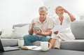 Frustrated senior couple, documents and debt on living room sofa in financial crisis, expenses or bills at home. Mature