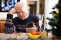 Frustrated senior man looking at phone during Christmas celebration Royalty Free Stock Photo