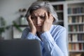 Frustrated senior retired woman touching head, looking at laptop screen Royalty Free Stock Photo