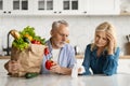 Frustrated Senior Spouses In Kitchen Checking Bills After Grocery Shopping Royalty Free Stock Photo