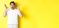 Frustrated and shocked guy panicking, screaming and looking scared, standing in white t-shirt over yellow background