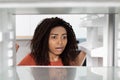 Frustrated shocked young african american female opens door refrigerator, looks and checks meal or ice