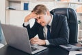 Frustrated stress Caucasian businessman touch his forehead while looking at the laptop and grinding his teeth, concept failure of