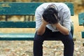 Frustrated stressed Asian business man with hand cover face sitting on the bench of public park and suffering from depression and Royalty Free Stock Photo