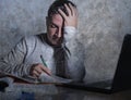 Frustrated and stressed young college student man working with textbook notepad and laptop computer at home desk feeling overwhelm Royalty Free Stock Photo