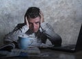 Frustrated and stressed young college student man working with textbook notepad and laptop computer at home desk feeling overwhelm Royalty Free Stock Photo