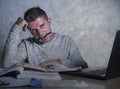 Frustrated and stressed young college student man working with textbook notepad and laptop computer at home desk feeling overwhelm Royalty Free Stock Photo