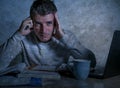 Frustrated and stressed young college student man working with textbook notepad and laptop computer at home desk feeling overwhelm Royalty Free Stock Photo