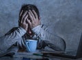 Frustrated and stressed young college student man working with textbook notepad and laptop computer at home desk feeling overwhelm Royalty Free Stock Photo