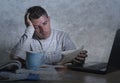 Frustrated and stressed young college student man working with textbook notepad and laptop computer at home desk feeling overwhelm Royalty Free Stock Photo