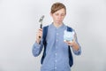 Frustrated student boy try to break a piggy bank using a hammer isolated over white background. Small amount of financial savings