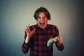 Frustrated teen boy playing video games isolated on grey wall background. Angry and upset guy gesturing with hand while holding Royalty Free Stock Photo