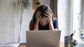 Frustrated unhappy laptop user girl touching head at work table